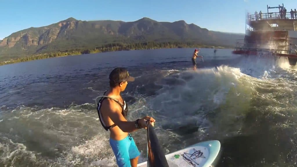 Surfer la vague en stand up paddle derrière un bateau